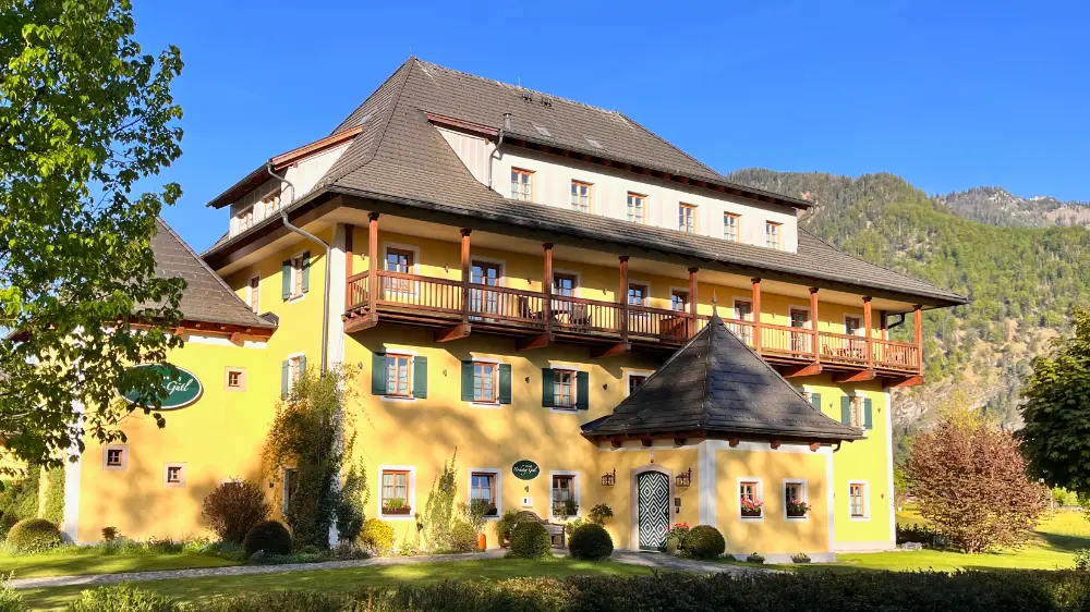 Boutique Hotel Hochsteg-Gütl at Lake Traunsee with yellow facade, balcony and views of the surrounding mountains